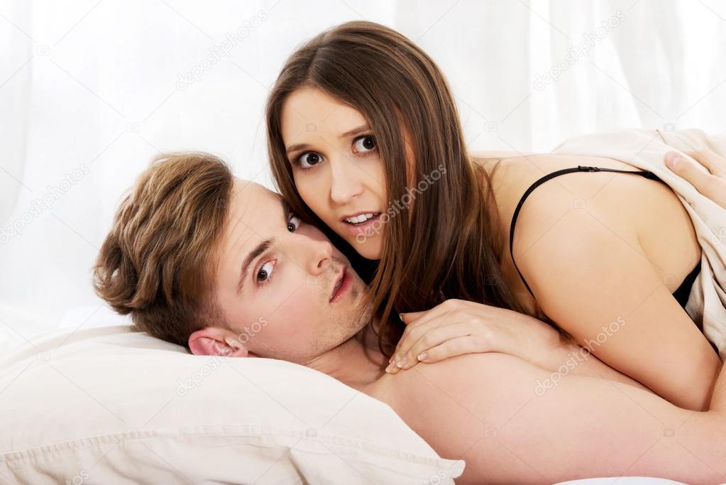 Young shocked couple lying on bed.