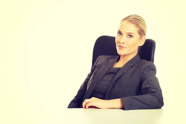 Mulher de negócios sorridente sentada na mesa — Fotografia de Stock