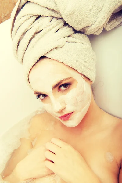 Woman relaxing in bathtub with face mask. — Stock Photo, Image