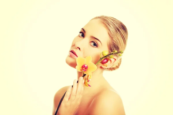 Schöne Kurfrau mit orangefarbener Orchidee — Stockfoto