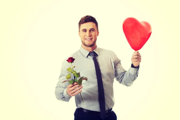 Jonge man met een rode roos en hart ballon. — Stockfoto