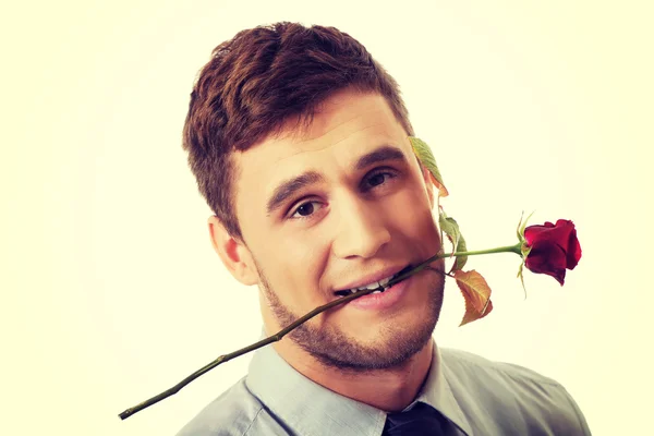 Szép ember tartja a vörös rózsa a szájában. — Stock Fotó