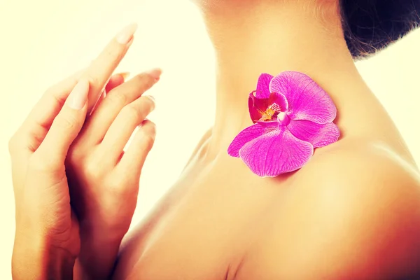 Mulher com pétala de orquídea roxa no ombro — Fotografia de Stock