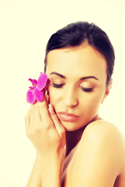 Mujer desnuda con pétalo de orquídea púrpura cerca de la cara — Foto de Stock