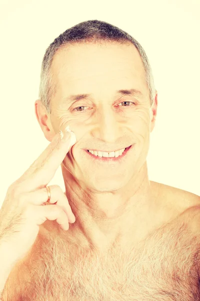 Homem aplicando creme em seu rosto — Fotografia de Stock