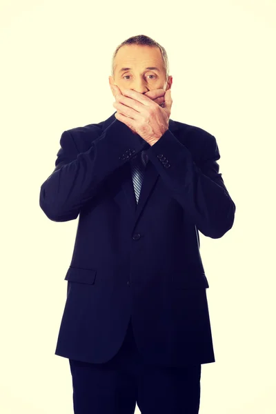 Mature businessman covering mouth — Stock Photo, Image