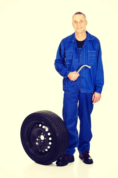 Full length mechanic with a tire and wrench — Stock Photo, Image