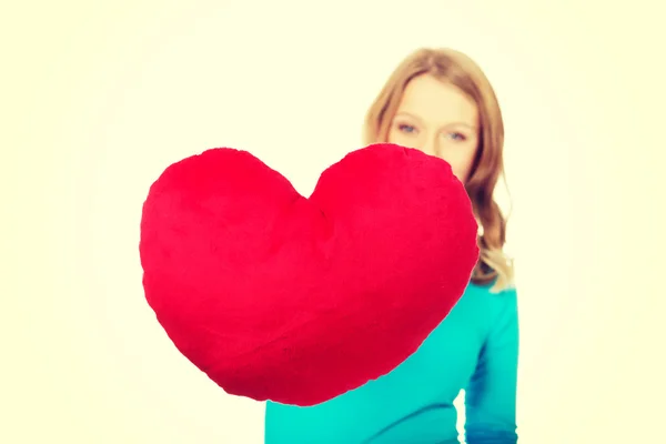 Young woman with heart shaped pillow — Stock Photo, Image