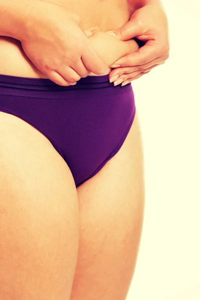 Женщина измеряет жировой живот в нижнем белье — стоковое фото