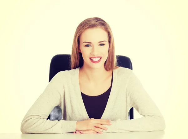 Hermosa mujer feliz y sonriente sentada junto a un escritorio . —  Fotos de Stock