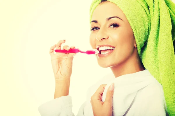 Retrato de una mujer en albornoz cepillándose los dientes — Foto de Stock