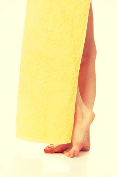 Pernas femininas cobertas com uma toalha amarela — Fotografia de Stock