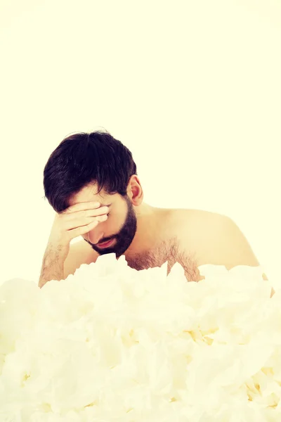 Hombre enfermo sentado con un montón de tejidos . — Foto de Stock