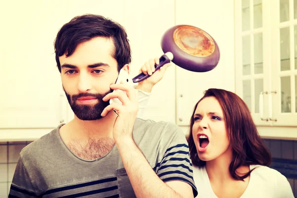 Angry young woman hitting men with frying pan. — Stock Photo, Image