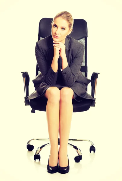 Sitting businesswoman with hands on chin — Stock Photo, Image