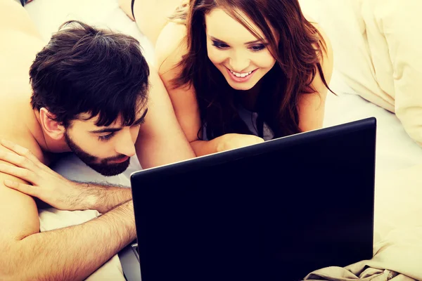 Pareja feliz en el ordenador portátil en el dormitorio . — Foto de Stock