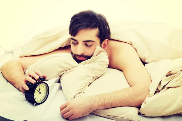 Hombre agotado siendo despertado por un despertador. — Foto de Stock