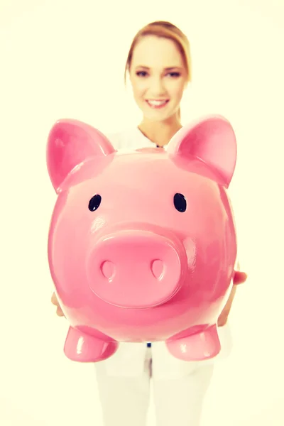 若い女医、piggybank を保持. — ストック写真