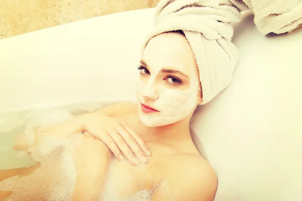 Woman relaxing in bathtub with face mask. — Stock Photo, Image