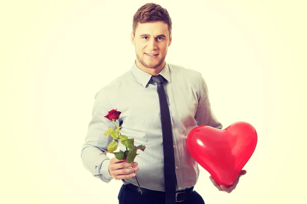 Joven con una rosa roja y un globo de corazón . — Foto de Stock