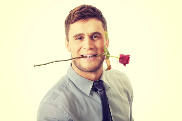 Knappe man met rode roos in zijn mond. — Stockfoto