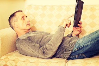 Evde dijital tablet kullanan olgun bir adam