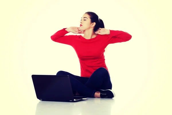 Zmęczona kobieta siedzi ze skrzyżowanymi nogami z laptopa — Zdjęcie stockowe
