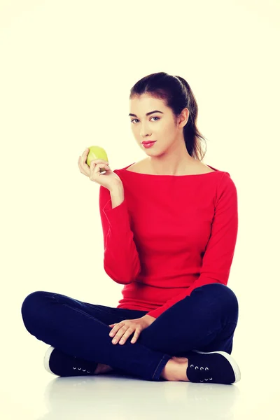 Γυναίκα που κάθεται σταυροπόδι κρατώντας ένα μήλο — Φωτογραφία Αρχείου