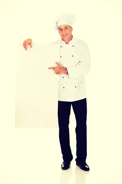 Szef kuchni w białym mundurze trzymając pusty transparent — Zdjęcie stockowe