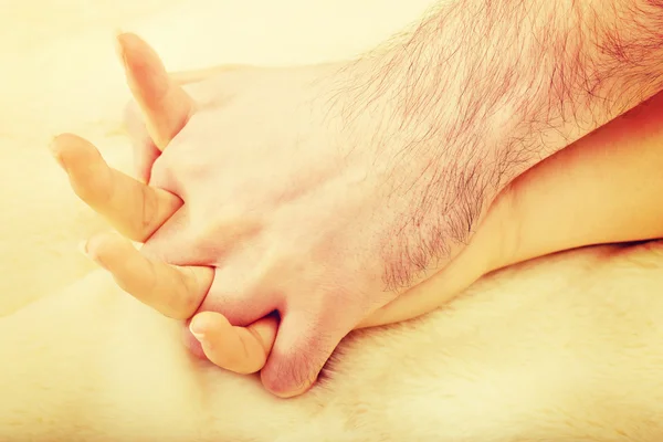 Hands of female and male lying on bed. — Stock Photo, Image
