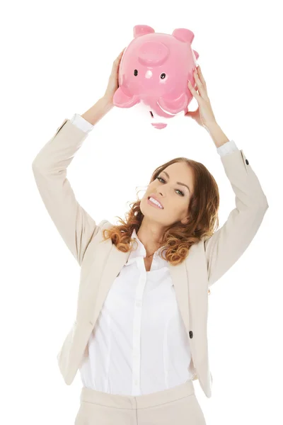 Businesswoman shaking a piggybank. — Stock Photo, Image