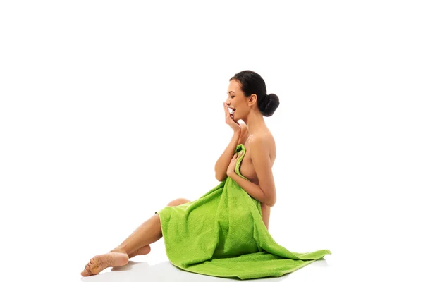 Mujer sonriente sentada envuelta en toalla — Foto de Stock