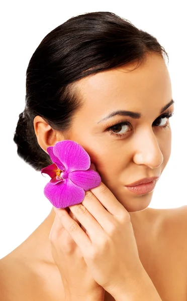 Kvinna med lila orkidé kronblad nära ansikte — Stockfoto