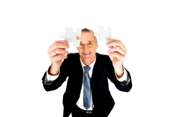 Geschäftsmann versucht Puzzleteile zu verbinden. — Stockfoto