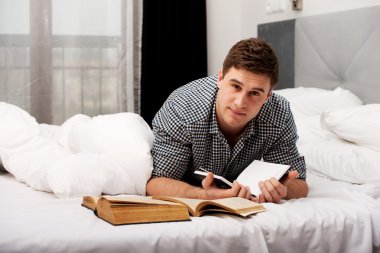 Onun yatakta bir kitapla düşünceli adam.
