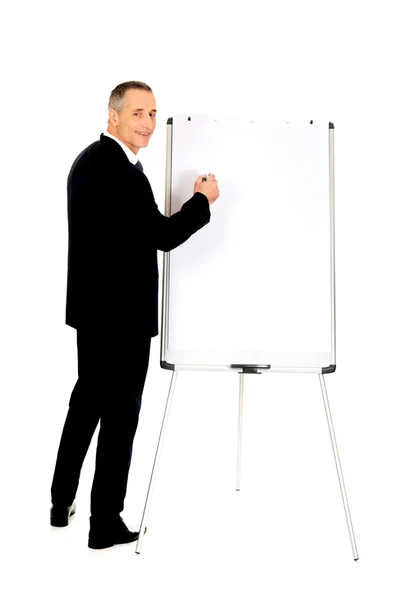 Male executive writing on a flipchart — Stock Photo, Image