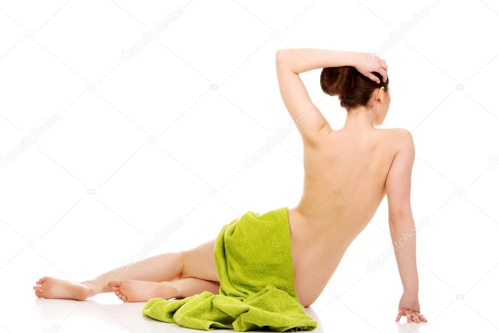 Woman lying wrapped in green towel.