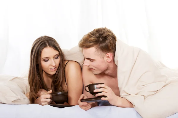ベッドでコーヒーを飲みながら幸せなカップル. — ストック写真