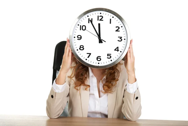 Mujer de negocios con reloj junto a un escritorio . Imágenes de stock libres de derechos