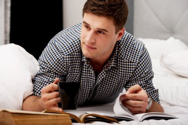 Onun yatakta bir kitapla düşünceli adam.