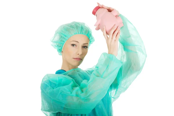 Worried doctor with pink piggy bank. — Stock Photo, Image