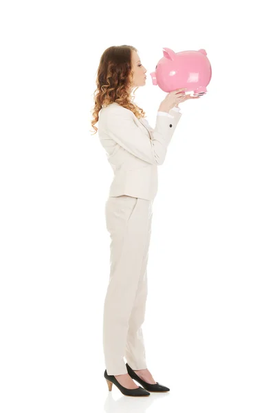 Businesswoman kissing a piggybank. — Stock Photo, Image