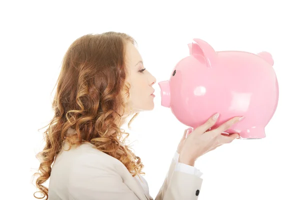 Geschäftsfrau küsst ein Sparschwein. — Stockfoto