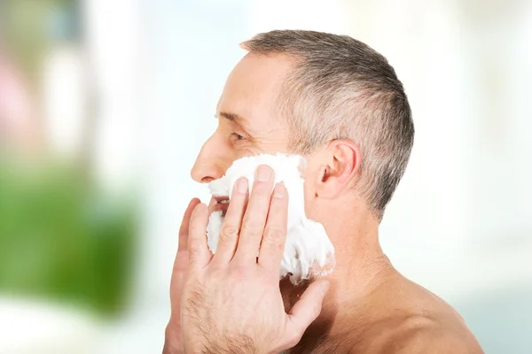 Homem maduro aplicando espuma de barbear — Fotografia de Stock