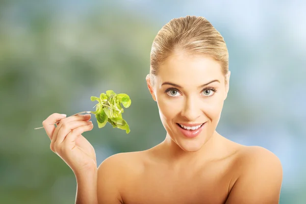 Mujer sonriente con un tenedor con lechuga — Foto de Stock