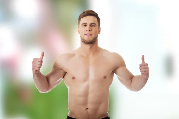 Sexy muscular homem mostrando polegares para cima . — Fotografia de Stock