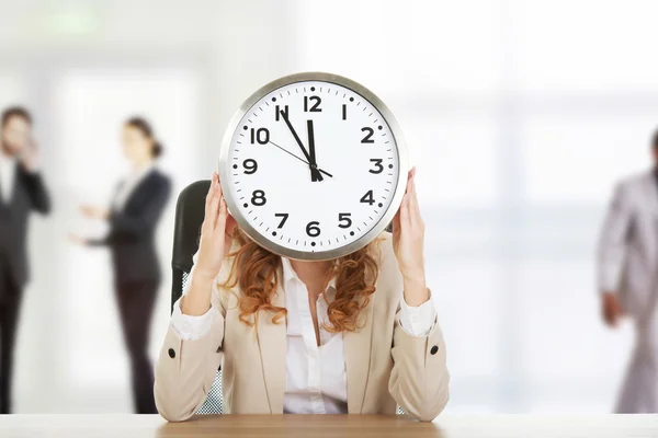 Femme d'affaires avec horloge par un bureau . — Photo