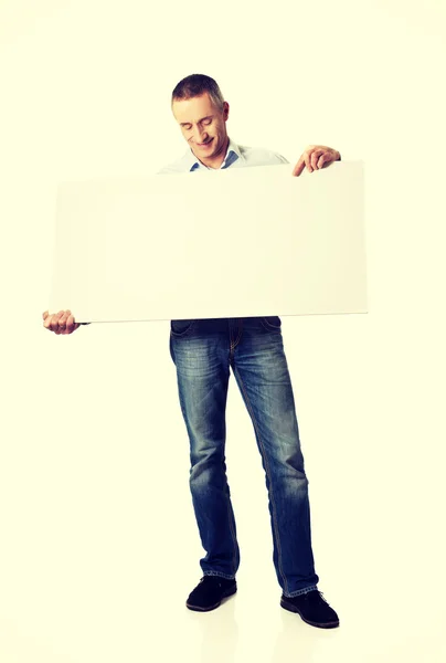 Hombre guapo sosteniendo una pancarta vacía — Foto de Stock