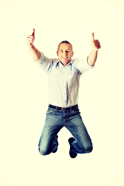 Mature man jumping with thumbs up — Stock Photo, Image