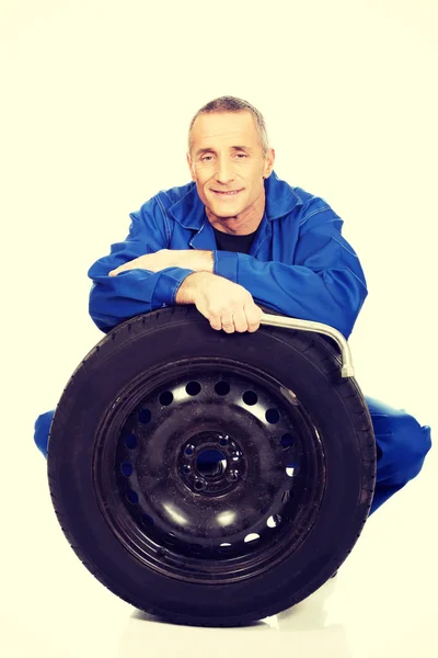 Happy mechanic with a tire and wrench — Stock Photo, Image